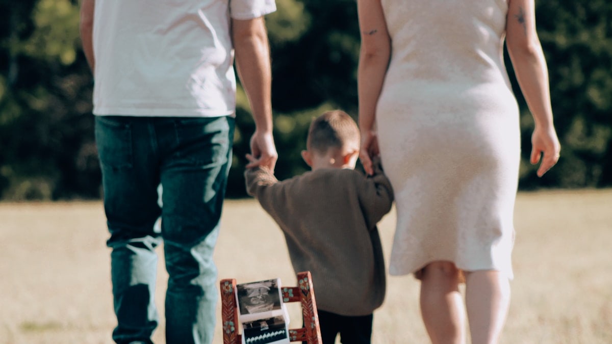 Family holds hands while looking at a baby ultrasound.
